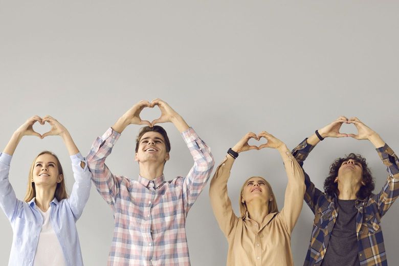 a row of people holding their hands up in heart shapes